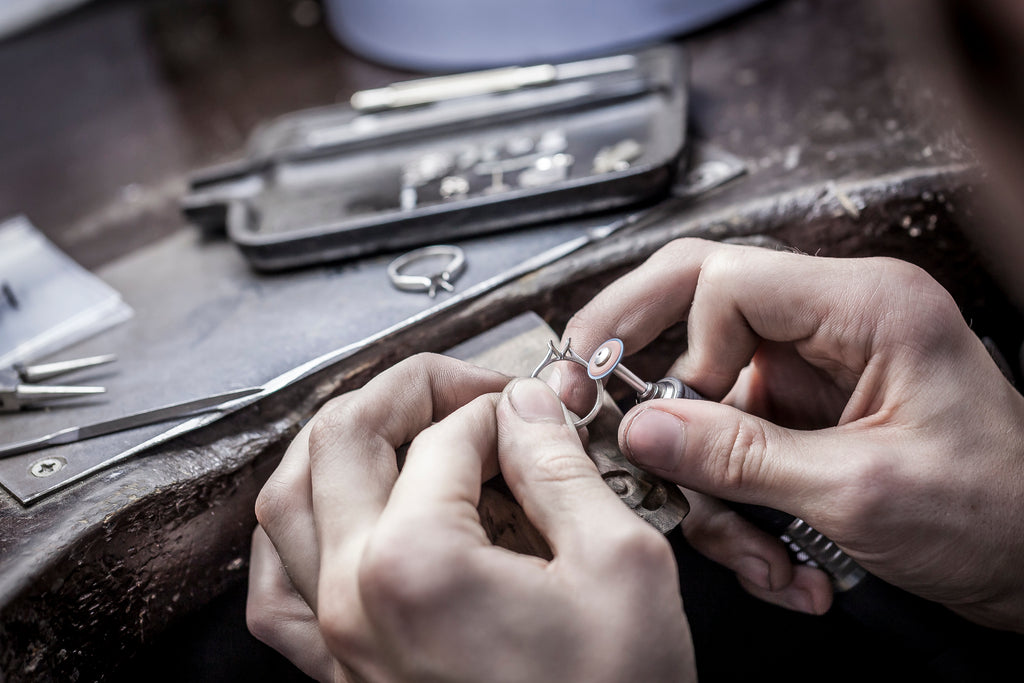 Over-shoulder shot of a man cutting an engagement ring band in a workshop